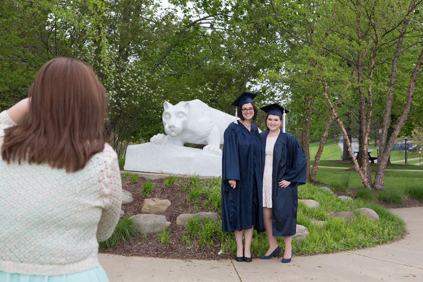 Jessica Findling and a friend pose in their caps and gowns in front of the Lion Shrine.