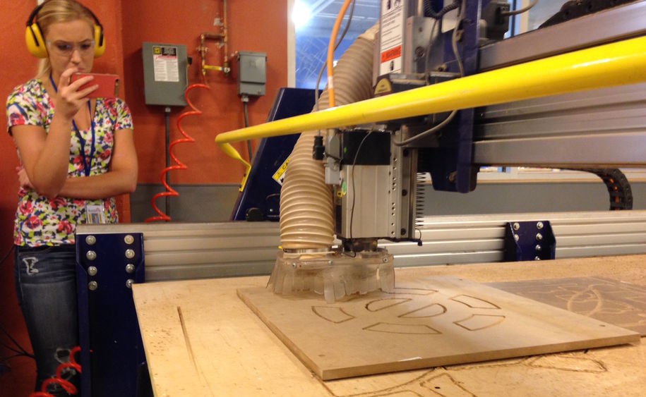 Engineering student Leah Berry records the ShopBot in action with her smart phone.