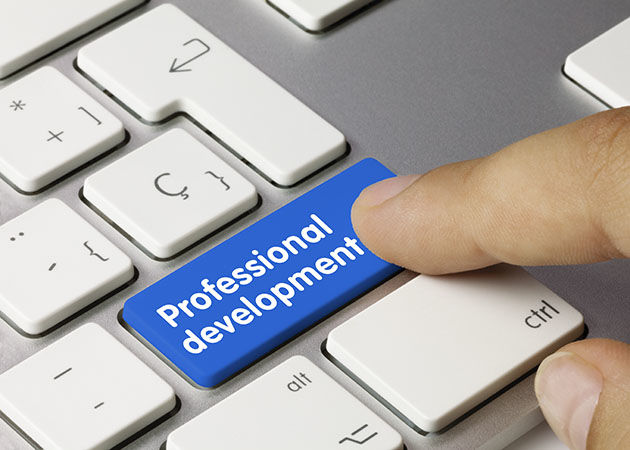 An index finger is about to push a button on a computer keyboard, but instead of a return key it is blue and says professional development.