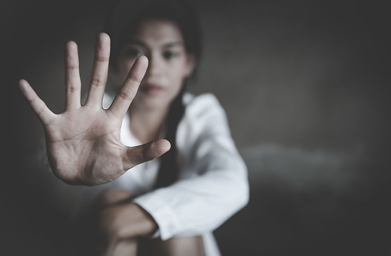 A photo of a young girl wearing white with her hand extended out, palm forward, towards the camera