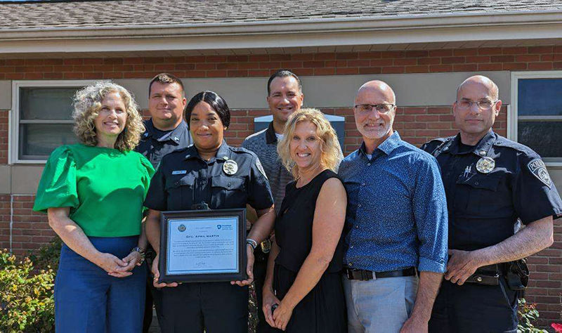 A photo of campus leadership and university officers with April Martin, in uniform, in the center holding an award plaque