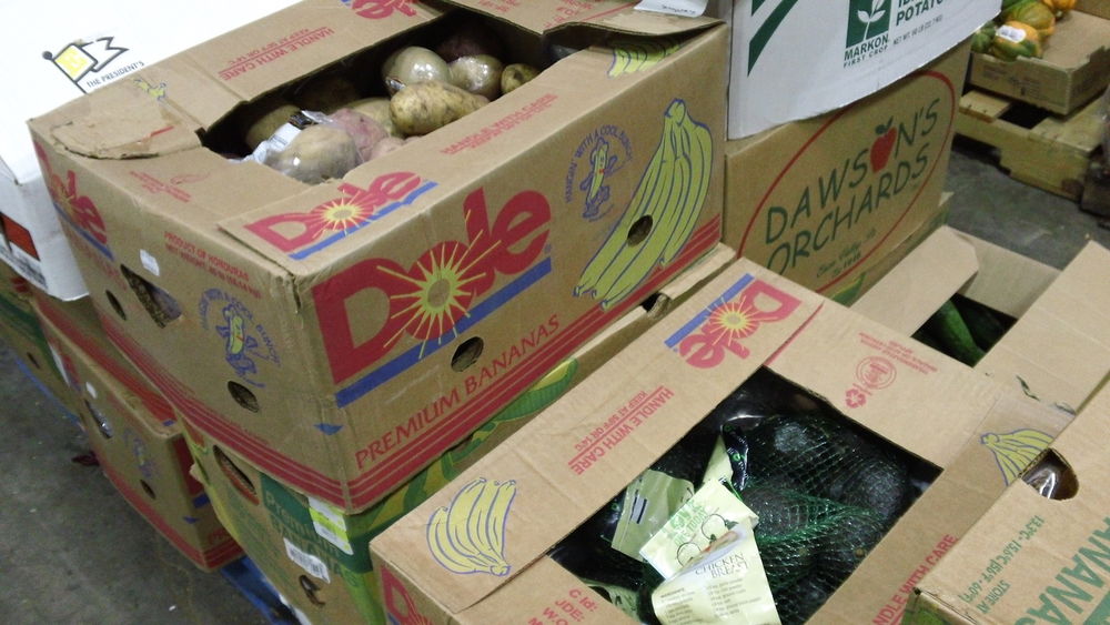 Boxes of food sit on the floor of the food bank warehouse.