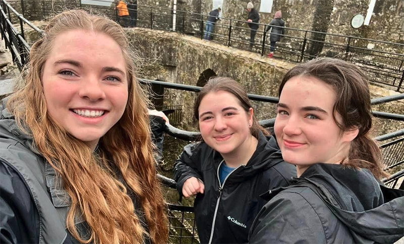 A group of female students stand in a courtyard at Blarney Castle.