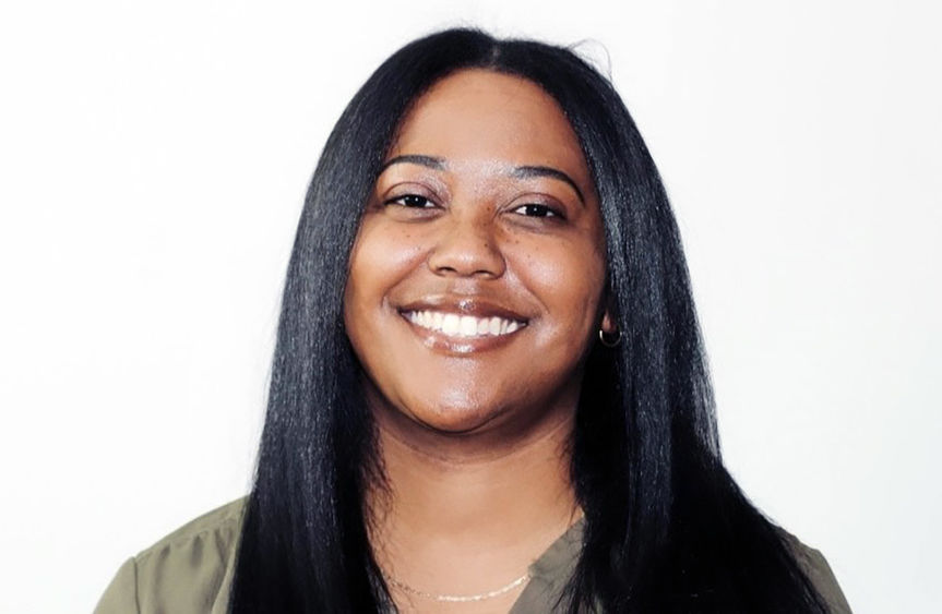 A photo of Maura smiling and wearing a green shirt on a white background