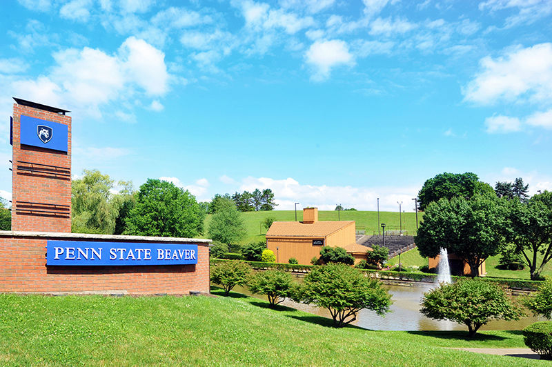 Penn State Beaver's entrance with a brick entrance wall with the campus name and the pond and amphitheater to the right. 