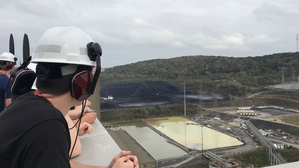 A student wearing a construction hat looks down from the 17th floor of a building.