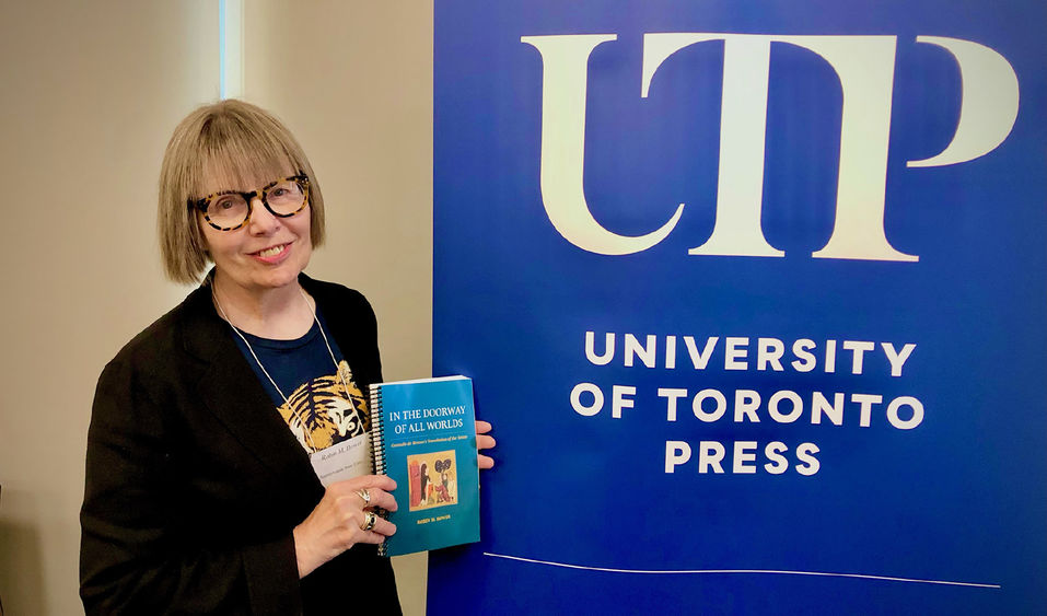 Robin Bower stands with her book in front of a UTP sign